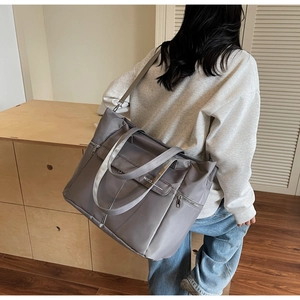 Modèle portant un grand sac cabas gris montrant la taille dans un décor d'intérieur