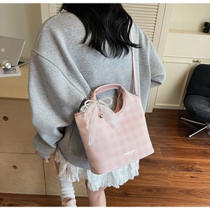 Rear view of a model wearing a pink plaid tote bag with pearl bow and lace charms