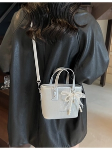 Silver mini tote bag with pearl bow charm and detachable shoulder strap in metallic finish