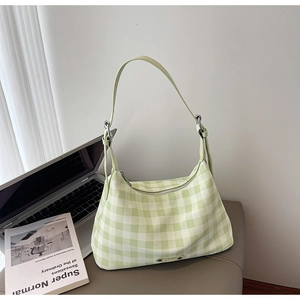 Détail du sac croissant à carreaux verts avec bandoulière sur un bureau épuré