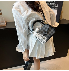 Lace bow detail on a plaid crossbody bag carried by a model in a casual setting