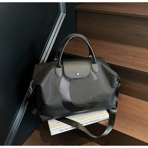 Detail of black large travel tote featuring matte letter C logo and leather handles
