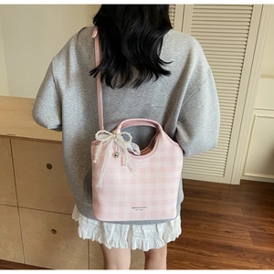 Detail of pink plaid tote bag featuring a pearl lace bow and brand logo print