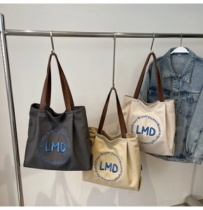 Detailed embroidery and leather handles on canvas tote bags in various colors