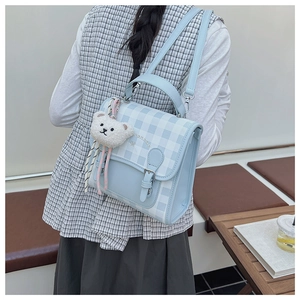 Détail du sac à dos à carreaux bleu et blanc avec breloque ours en peluche et boucle métal