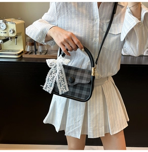 Detail of checkered crossbody bag with large round button and white lace bow accessory