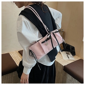 Close-up of pink ruched shoulder bag with black bows and heart pendant detail