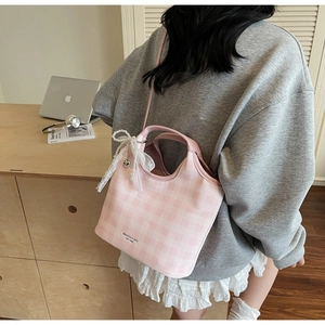 Detailed view of pink plaid shoulder bag with lace bow and pearl heart charm on a model