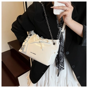 Détail du sac bandoulière blanc brillant avec nœud, chaîne et logo métallique