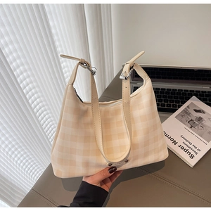 Détail du sac à carreaux crème avec bandoulière réglable et plaque logo en métal