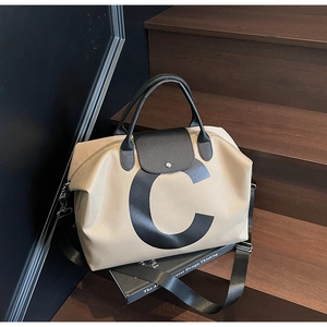Detailed view of beige canvas tote bag with black leather flap and iconic C letter
