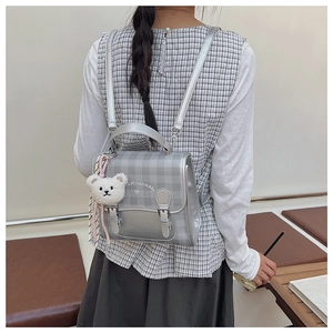 Détail du mini sac à dos argenté à carreaux avec breloque ours et sangle tressée déco