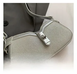 Close-up of metallic silver underarm bag featuring a textured fabric and shiny hardware lock