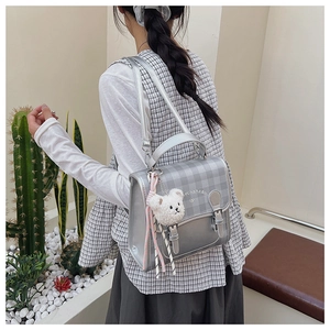 Vue détaillée d'un mini sac à dos argenté à carreaux avec un petit ours en peluche