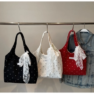 Détail de sacs fourre-tout en toile noir, rouge et blanc avec grands nœuds en dentelle