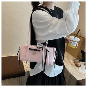 Pink patent leather shoulder bag with bow and heart pendant shown on model
