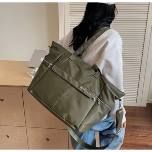 Grand sac fourre-tout vert olive avec poche avant et bandoulière porté par mannequin