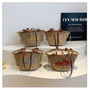 Détail de sacs fourre-tout en paille faits main avec poignées en cuir et broderie Hello de plage
