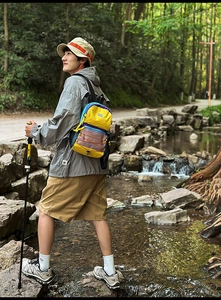Detail view of contrast color outdoor backpack with front mesh pocket in forest setting