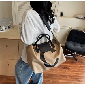 Detail of khaki waterproof nylon travel tote with black leather handles and letter C print