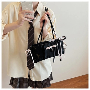 Detail of black nylon shoulder bag with cute pink ribbon bows and metallic pendant charm