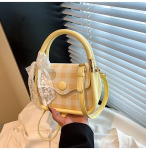 Detail of yellow checkered handbag with white lace bow and round buckle close-up