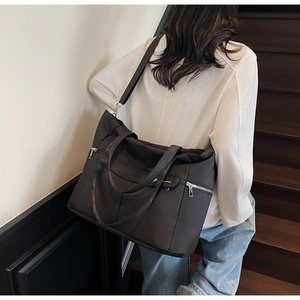 Modèle portant un grand sac cabas noir avec poche zippée latérale dans un escalier