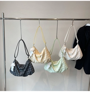 Detail view of plaid tote bags in four colors with bear charms on a clothing rack