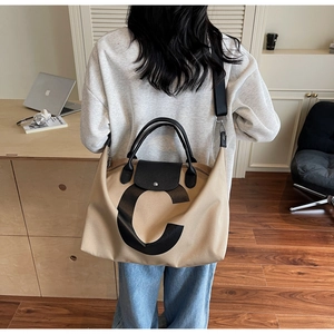 Macro detail of large canvas tote bag showing black leather handles and printed letter C logo