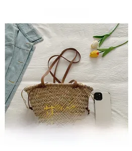 Détail du sac cabas en paille tressée avec broderie Hello jaune et anses en cuir marron