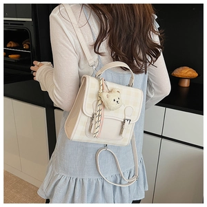 Gros plan du mini sac à dos à carreaux avec breloque ours et détails de boucles argentées