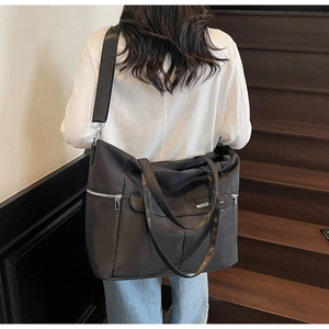 Détail du sac cabas en nylon noir avec fermetures éclair argentées et texte NOCO blanc