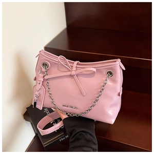 Vista dettagliata della borsa rosa chic con fiocco grande e tracolla a catena argento