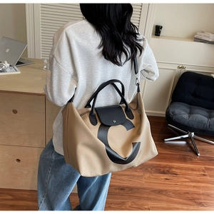 Detail of khaki canvas tote bag with black leather handle and bold letter C print