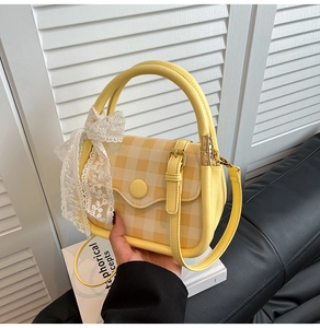 Detailed macro view of yellow checkered handbag with lace bow and leather strap