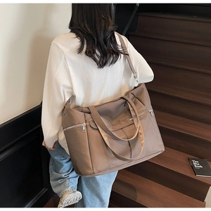 Grand sac fourre-tout marron en nylon avec poches zippées porté par un mannequin en ville