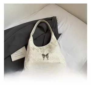 Détail du sac hobo en jacquard beige avec ornement papillon en métal argenté et texture