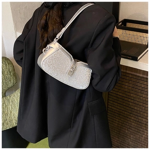 Detail showing glittery silver texture and metal buckle of asymmetric saddle bag
