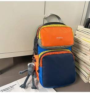 Detail of color block backpack with plush frog keychain and APASTTCA logo for students