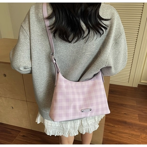 Détail du sac demi-lune à carreaux lavande porté en bandoulière sur le dos d'un modèle