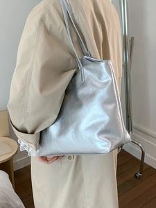 Bolso tote grande plateado metalizado con asas finas mostrado en una modelo de estilo minimal