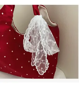 Détail du sac cabas en toile fleurie avec nœud en dentelle blanche et étiquette de marque