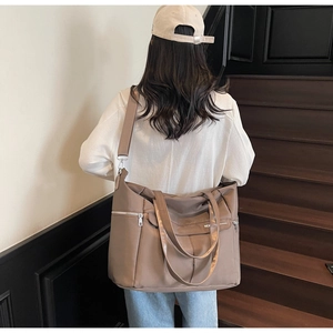Détail du grand sac cabas en nylon marron porté à l'épaule dans un décor moderne épuré