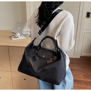 Close-up of large black nylon tote bag with leather handles shown in a home setting
