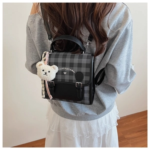 Close-up of a checkered mini backpack with plush bear charm and contrast strap detailing