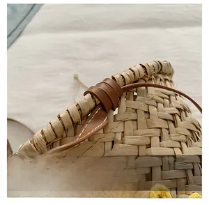 Détail du tissage en paille et de la bandoulière en cuir marron avec surpiqûres