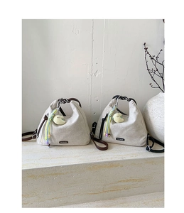 Detail of canvas tote bags with leather handles, moon plush charms and bead decor