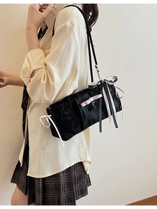 Fashionable black nylon shoulder bag with pink ribbon and heart pendant on model
