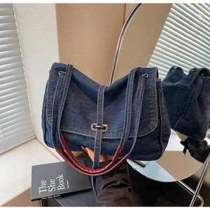 Detail of vintage denim shoulder bag with metal twist lock and red leather handle