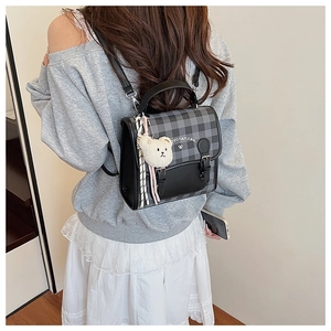 Détail du mini sac à dos à carreaux avec breloque ours en peluche et bordures cuir